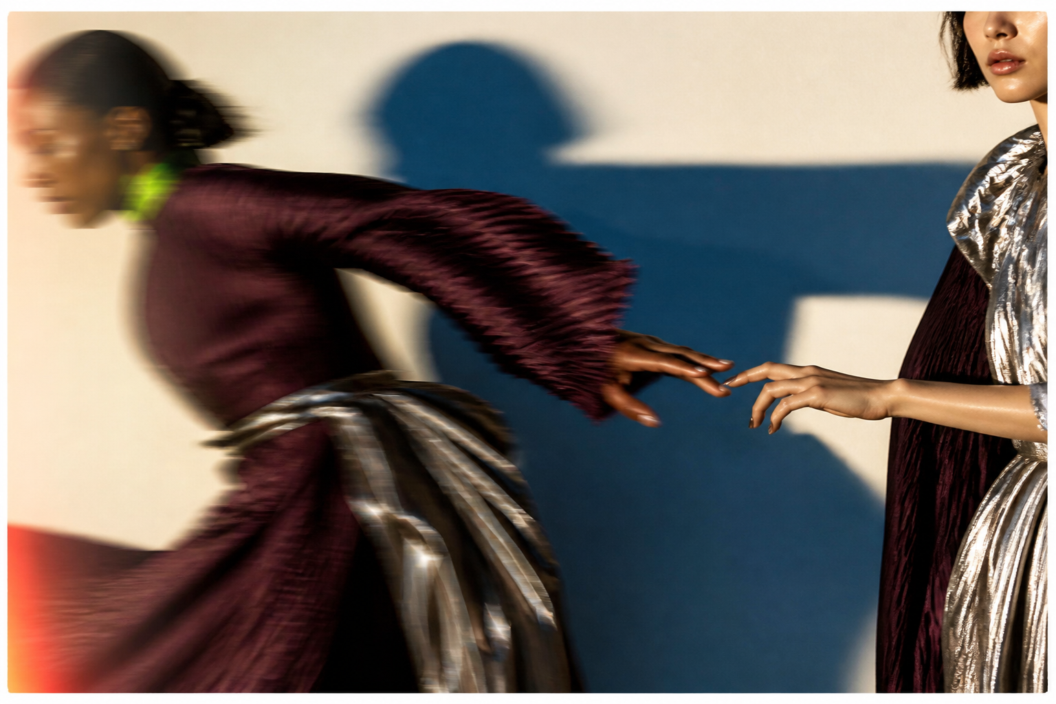 Deux silhouettes de mode se rejoignent dans un geste en mouvement